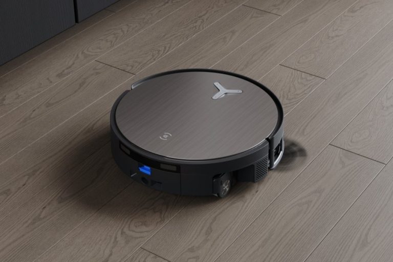 A modern robot vacuum cleaning a sunlit living room with hardwood floors.